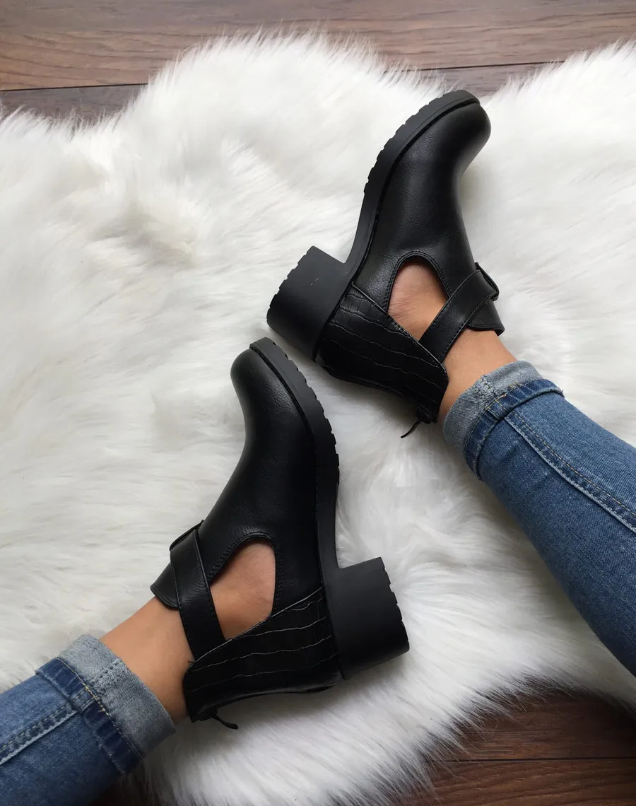 Black cutout ankle boots with small heel and buckle.